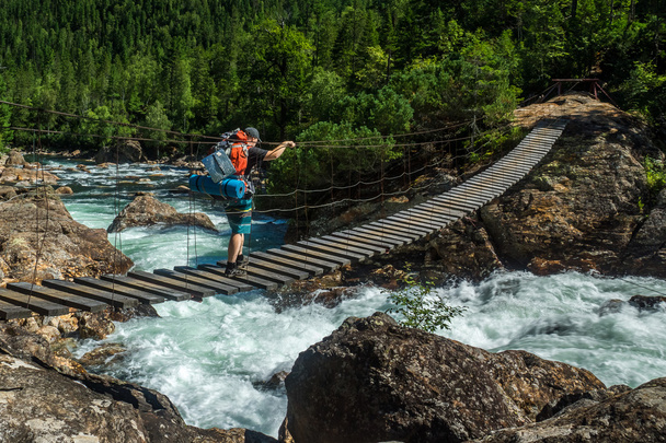 Tourist passes on the suspension bridge over the Selenginka River - 写真・画像
