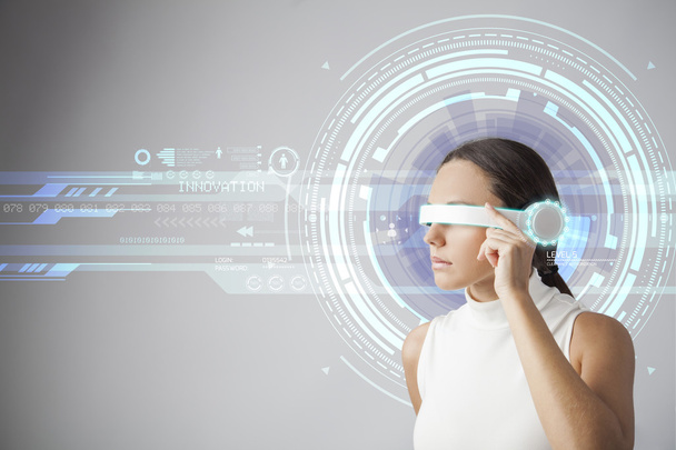 Young woman with futuristic smart glasses over gray background - Fotó, kép