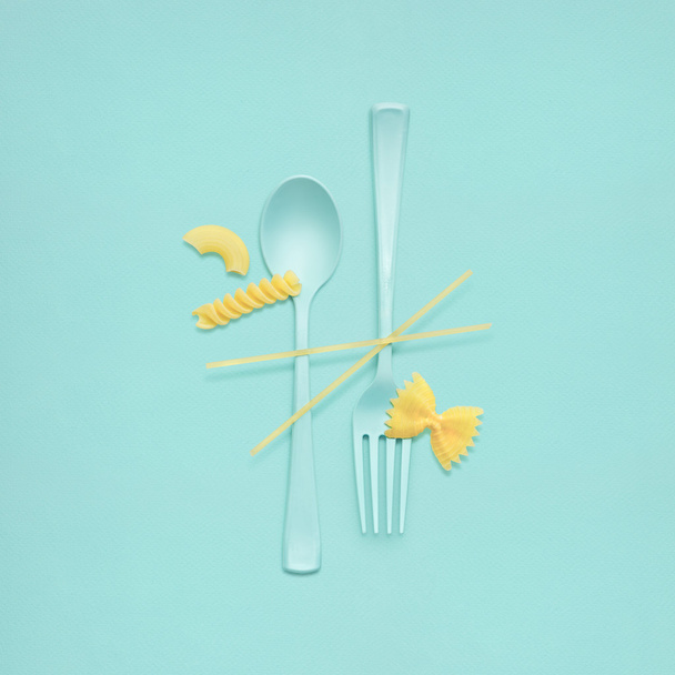 Tasty pasta. Creative still life of fork and spoon at a lunchtime with raw pasta served. - Photo, Image