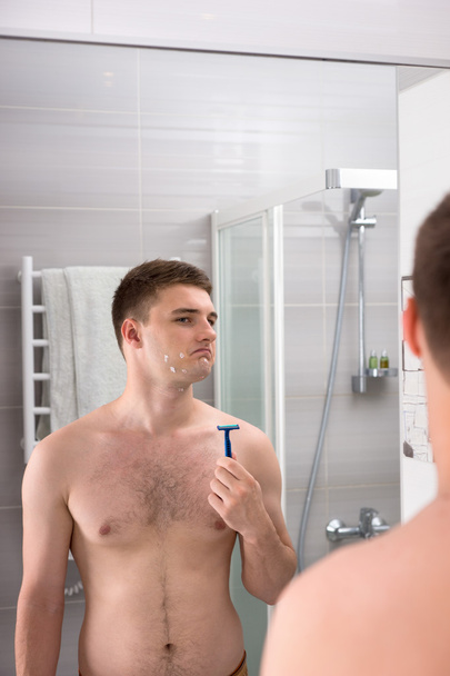 Handsome male  with cuts on his face after bad shaving  holding  - Foto, Bild