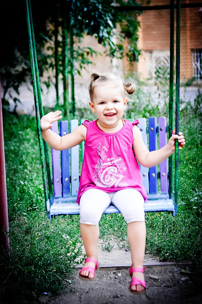 Una niña montado en un columpio en el parque
 - Foto, Imagen