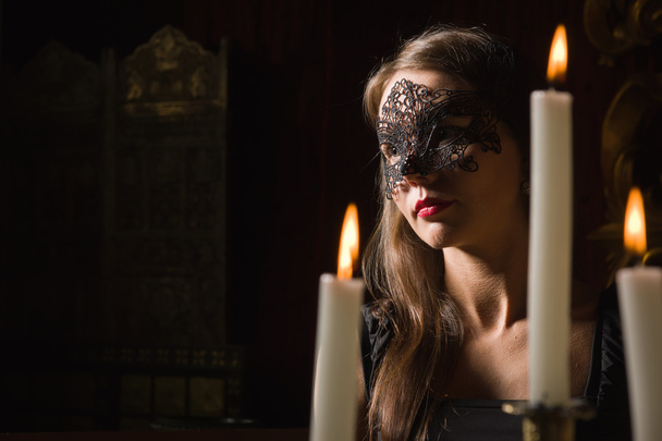 Módní sexy brunet žena nosí černé šaty a masku v ložnici - Fotografie, Obrázek