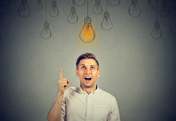 happy young man pointing at light bulb has a solution  - 写真・画像