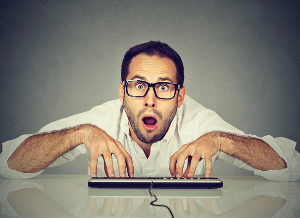 Crazy nerdy looking man in glasses typing on keyboard - 写真・画像