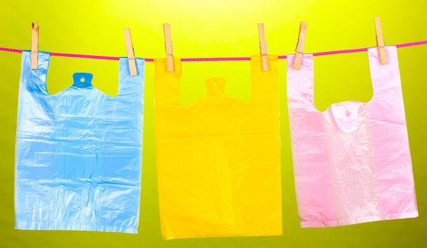 Cellophane bags hanging on rope on green background - Фото, изображение