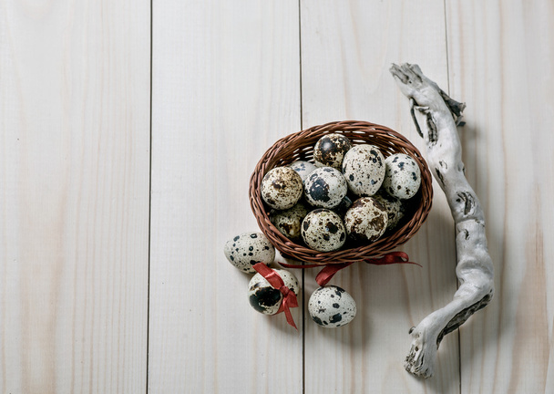 Quail eggs in little basket on wooden board. Easter decoration. - Foto, Imagen