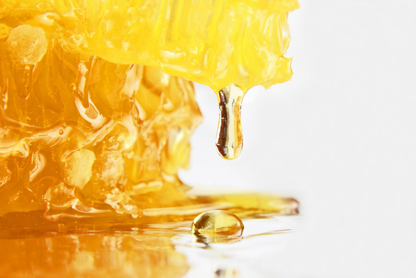drop of honey dripping from the honeycomb closeup - Fotoğraf, Görsel