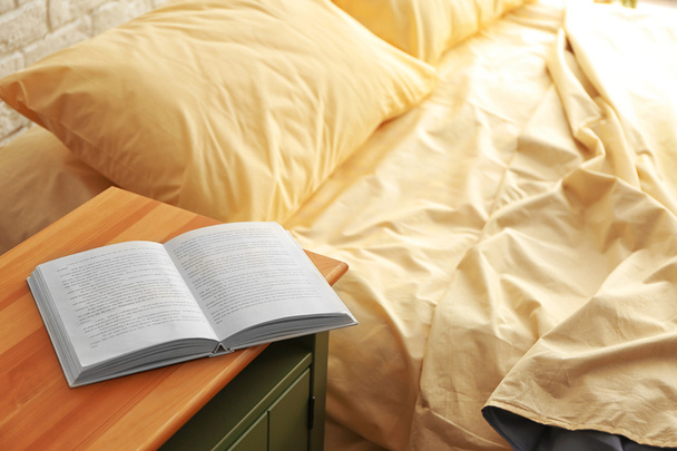 Opened book on wooden bedside - Foto, Bild