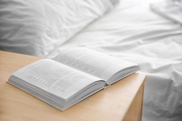 aufgeschlagenes Buch auf hölzernem Bett - Foto, Bild