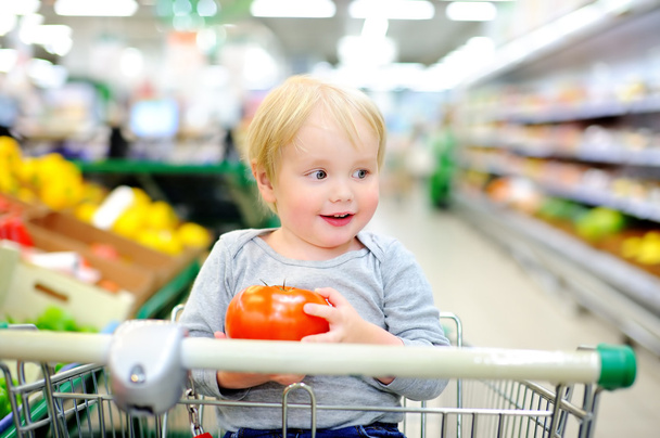Toddler sitting in the shopping cart in a supermarket - Foto, Bild