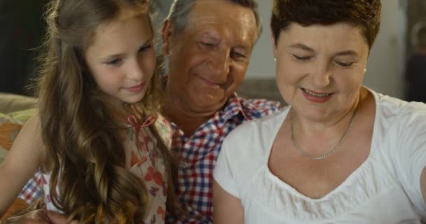 Mehrgenerationenfamilie aus Großvater, Enkelin und Großmutter schaut sich zu Hause ein Fotoalbum an - Filmmaterial, Video