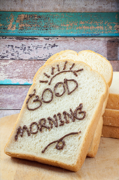 Kromka chleba z czekolady i słowo "dzień dobry" na śniadanie na podłoże drewniane - Zdjęcie, obraz