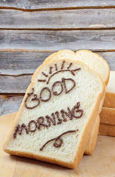 Rebanada de pan con chocolate y la palabra "buenos días" para el desayuno
  - Foto, imagen