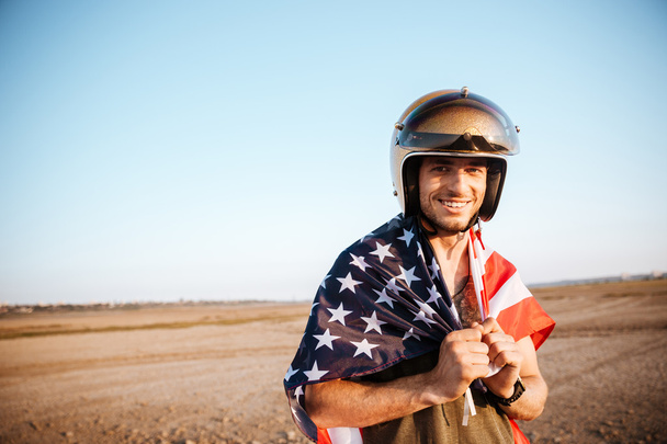Mies yllään Amerikan lippu viitta ja kultainen katselee kameraa
 - Valokuva, kuva