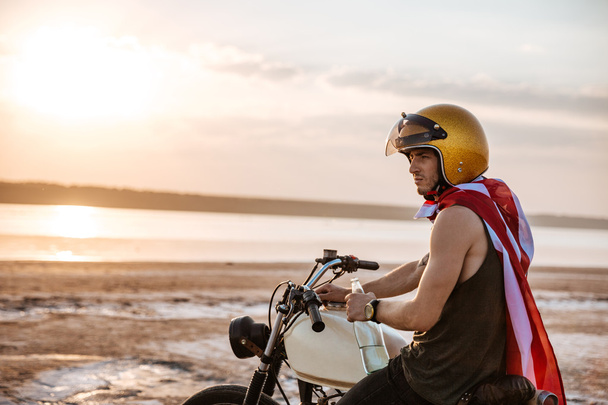Hombre de oro en capa americana sentado en su motocicleta
 - Foto, Imagen