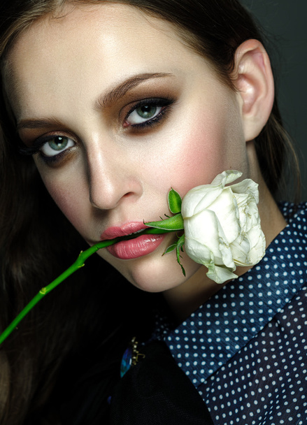Αίγλη πλάνο του μια κοπέλα ομορφιά με τριαντάφυλλο στο στόμα - Φωτογραφία, εικόνα