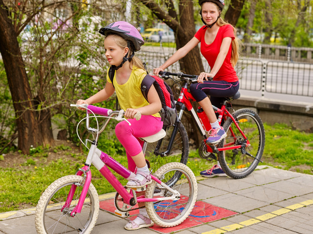 Dzieci dziewczyny, jazda na rowerze na pas żółty rower. - Zdjęcie, obraz