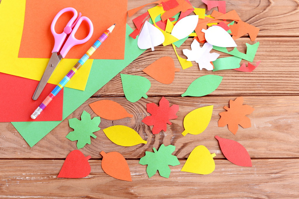Feuilles de papier coloré, ciseaux, crayon, feuilles de papier coloré automne sur fond en bois. Couper avec des ciseaux. Développement des compétences pour un tout-petit ou un enfant d'âge préscolaire. Vue du dessus
  - Photo, image