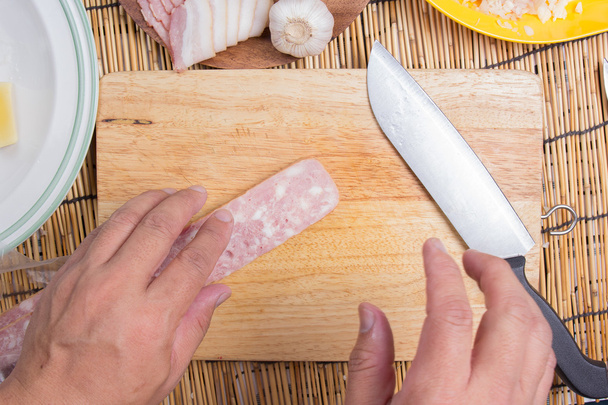 Шеф-кухар ріже бекон з ножем перед приготуванням
 - Фото, зображення