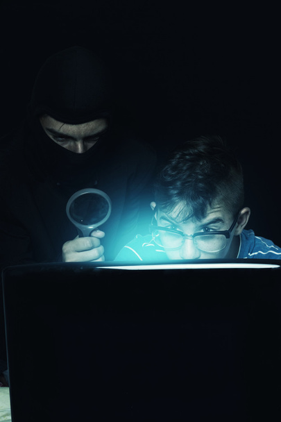 masked man spying data from notebook of teen - Valokuva, kuva