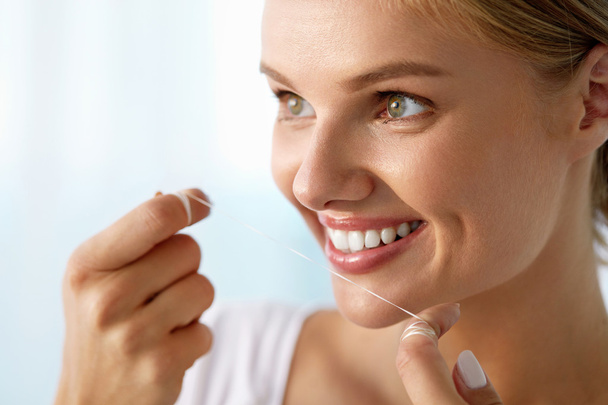 A fogak egészsége. Szép, mosolygós nő fogselyem egészséges fehér fogak - Fotó, kép