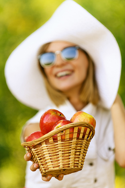 Nainen wiht paju kori pitää punainen omenat
 - Valokuva, kuva