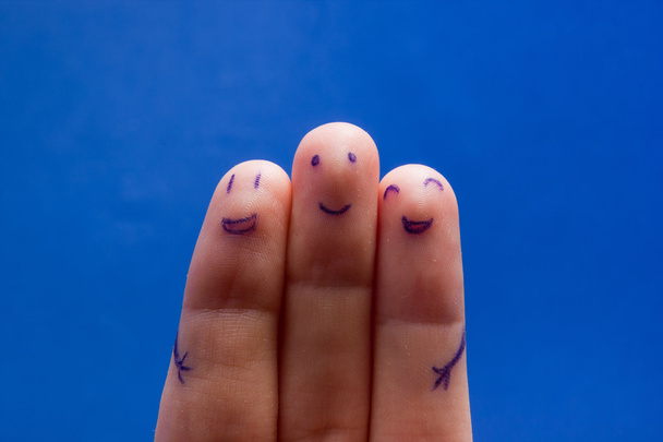 Kolme hymyilevää sormea, jotka ovat iloisia ystävyydestään. Ystävyys tiimityöskentely konsepti sinisellä pohjalla kopioi tilaa mainoksen tekstiä
. - Valokuva, kuva