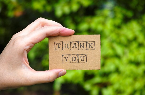 Woman hand holding cardboard card with words Thank You - Фото, изображение