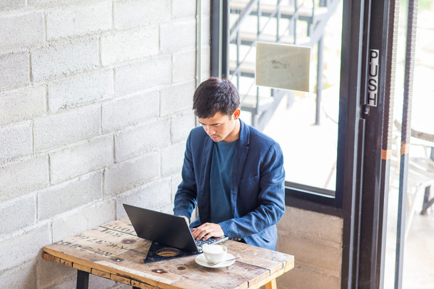 zakenman slijtage pak met behulp van laptop en latte-koffie drinken in café - Foto, afbeelding