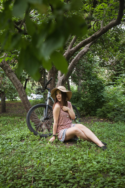 ragazza seduta sull'erba vicino alla bicicletta
 - Foto, immagini