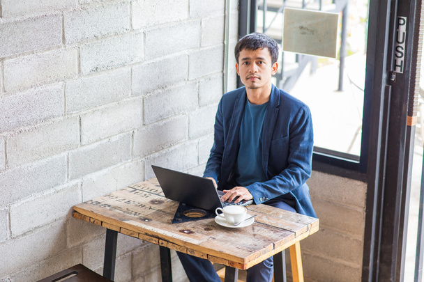 zakenman slijtage pak met behulp van laptop en latte-koffie drinken in café - Foto, afbeelding