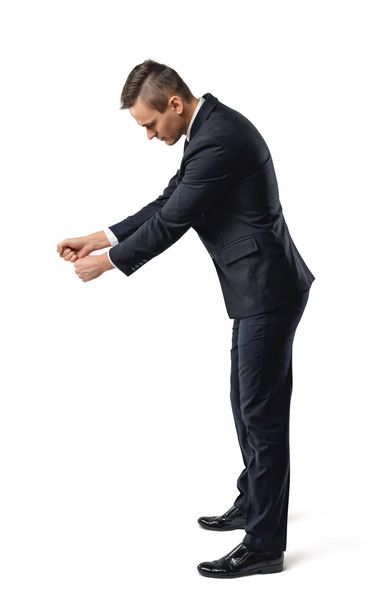 Side view of a businessman looking downwards and holding something isolated on white background - Photo, image
