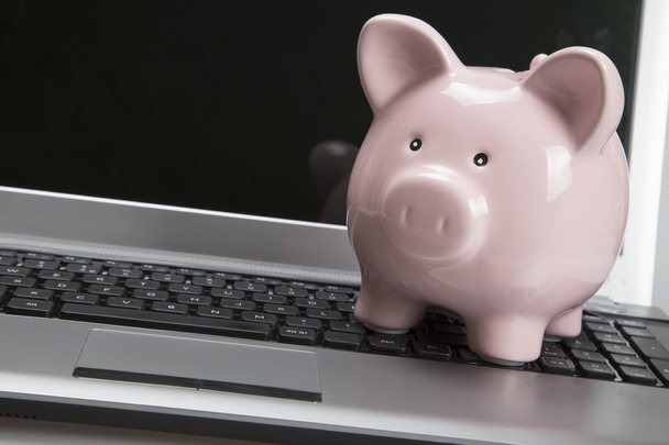 Piggy banco no teclado do laptop com tela em branco
 - Foto, Imagem