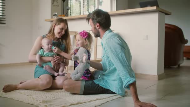 Bella giovane famiglia: mamma, papà, figlioletta e figlioletto sono seduti sul pavimento della cucina. Rallentatore
 - Filmati, video