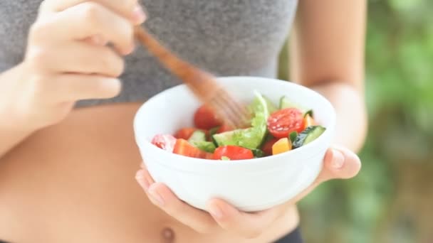 Young girl eating a vegetable salad after a workout . - Filmati, video