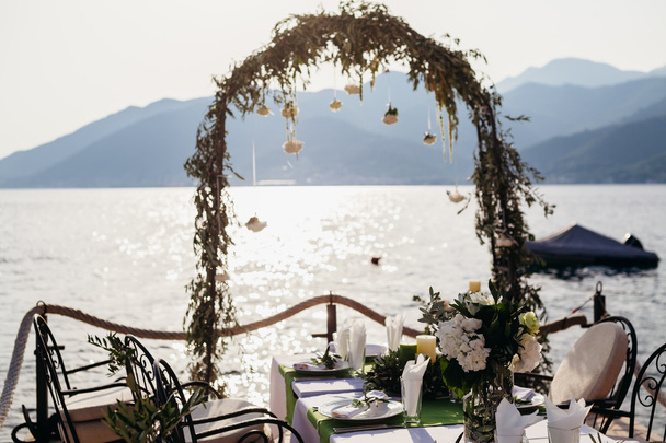 Свадебная арка назначения и банкует покрытый стол на закате
 - Фото, изображение