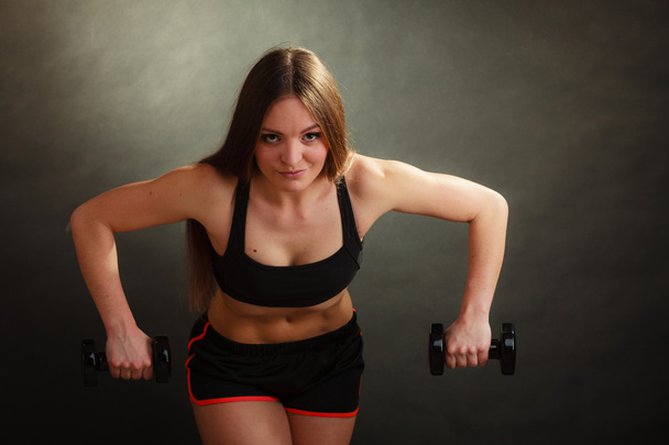Fit woman exercising with dumbbells. - Фото, изображение