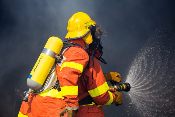 2 bomberos utilizan boquilla hidrante luchando con fuego envolvente con da
 - Foto, Imagen
