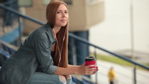 Young beautiful pretty girl sitting on the street with a cup of coffee. - Filmmaterial, Video
