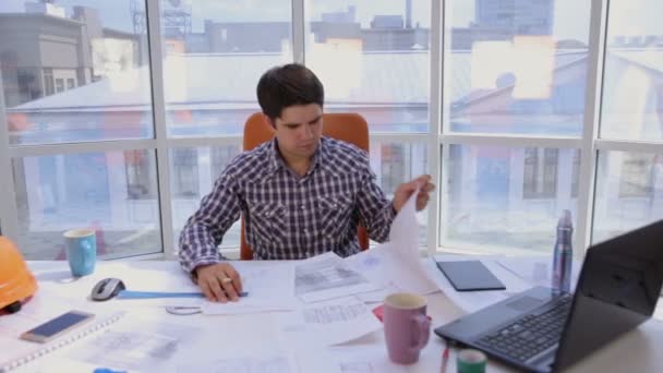 Un hombre de negocios seguro y atractivo que trabaja con dibujos, planos en una oficina ligera y moderna. Concepto empresarial
. - Metraje, vídeo