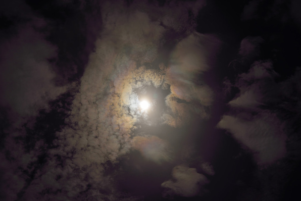 Full moon shining glowing light through the darkness of cloudy n - Photo, Image