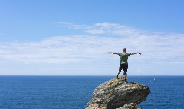Homme au sommet du rocher, regardant la mer
 - Photo, image