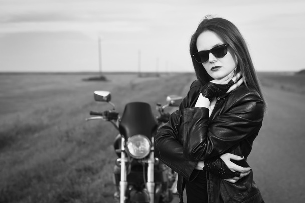Biker girl in a leather jacket posing near motorcycle - Foto, afbeelding