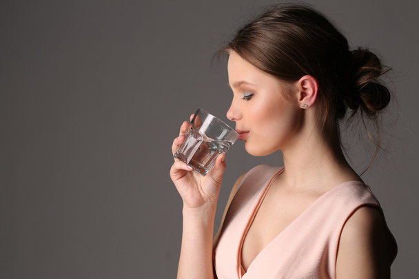 Girl drinking water. Close up. Gray background - Photo, image