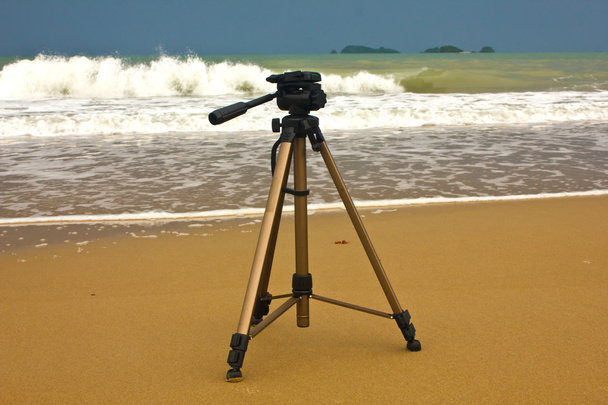 Trípode de cámara con fondo natural sobre arena
 - Foto, imagen
