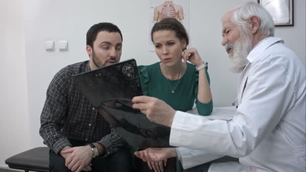 Male Senior Doctor showing a couple a x-ray in a office. - Filmmaterial, Video