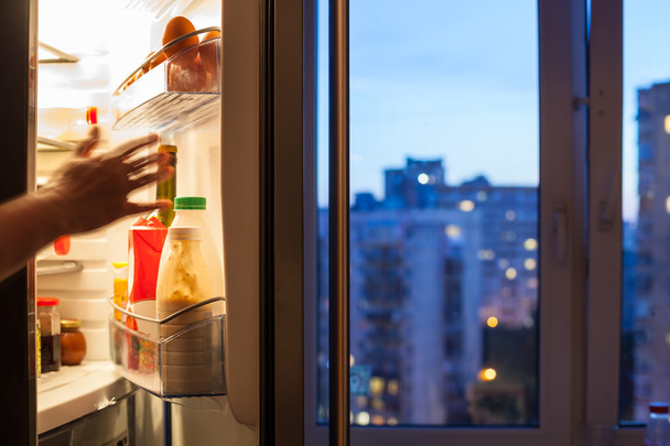 hand reaches to refrigerator and view of city - Photo, Image