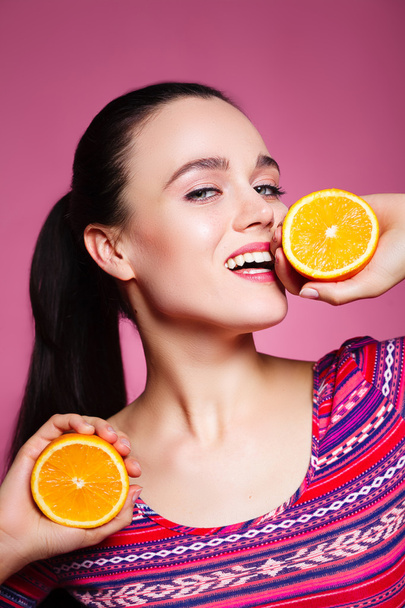 Portrait of comic happy girl holding halves of orange near face, - Foto, immagini