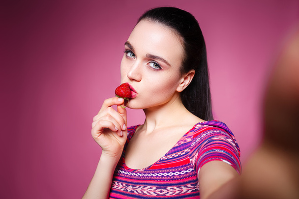 beautiful girl makes selfie and eating strawberries. - Fotografie, Obrázek