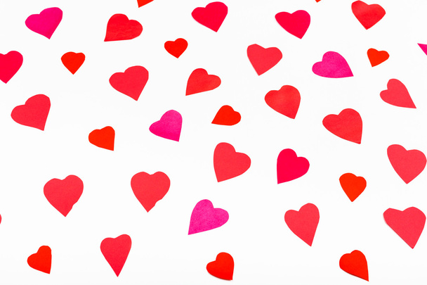 Kağıt beyaz üzerine pembe ve kırmızı kalpler kesip - Fotoğraf, Görsel
